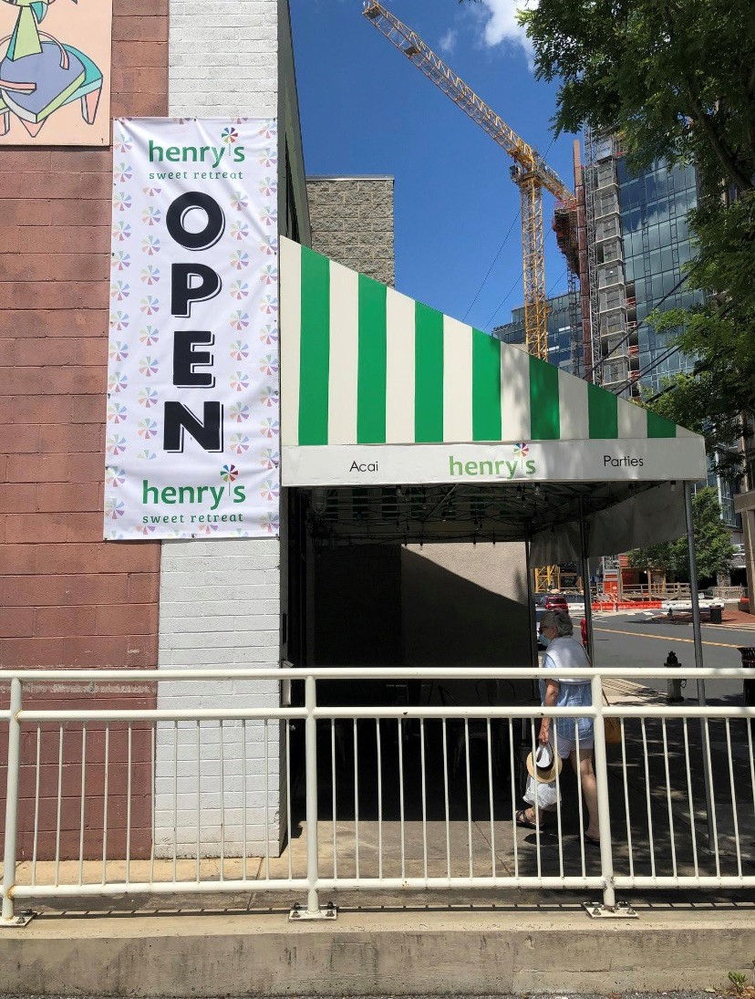 Promotional outdoor banner for Henry’s Sweet Retreat announcing the store is open.